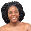 Woman wearing oversized black satin bonnet designed for overnight luxury hair protection
