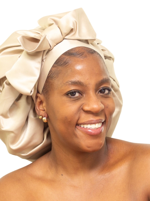 Woman wearing oversized champagne satin bonnet with soft structured luxury silhouette.