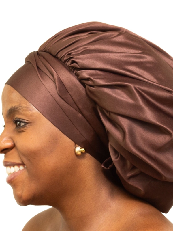 Woman wearing oversized chocolate brown satin bonnet designed for luxury overnight hair protection.