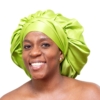 Woman wearing oversized lime green satin bonnet designed for luxury overnight natural hair protection.