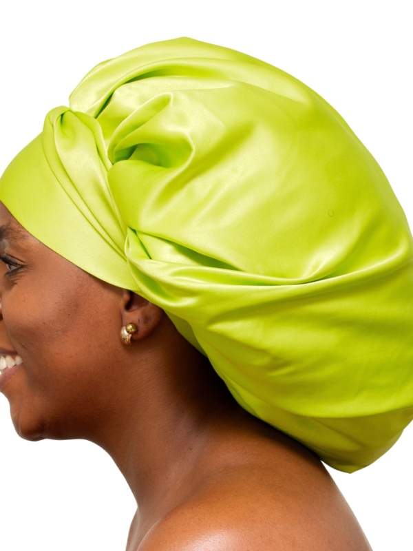 Woman wearing oversized lime green satin bonnet designed for luxury overnight natural hair protection.
