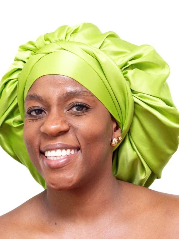 Woman wearing oversized lime green satin bonnet designed for luxury overnight natural hair protection.