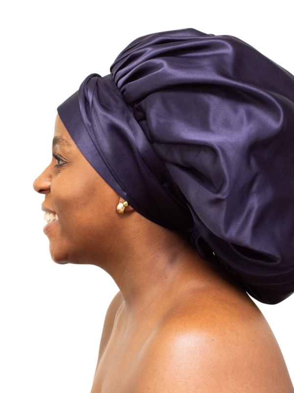 Woman wearing oversized navy satin bonnet for luxury natural hair protection.