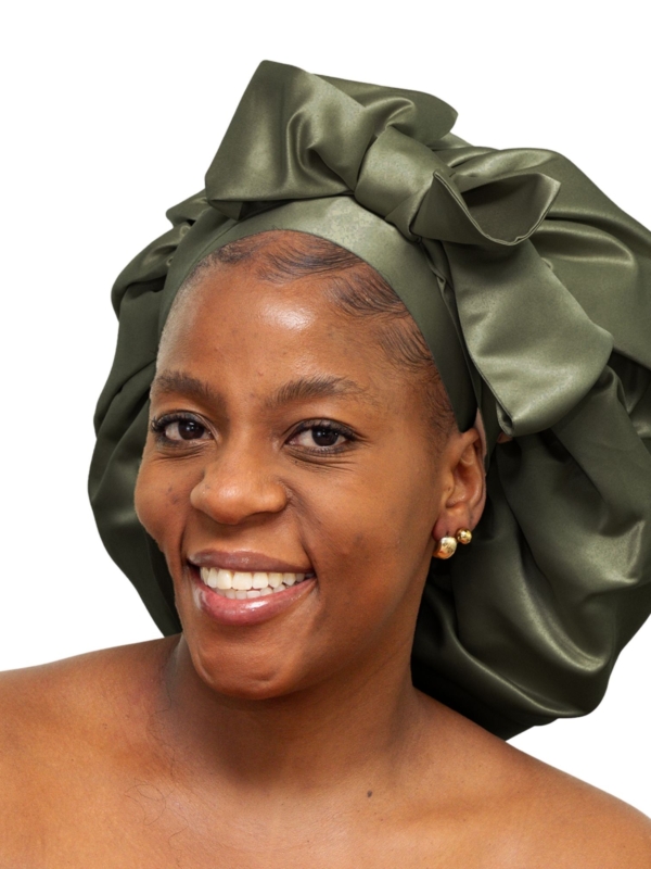 Woman wearing oversized deep olive satin bonnet designed for luxury overnight natural hair protection.