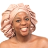 Woman wearing oversized rose gold satin bonnet designed for luxury overnight hair protection.