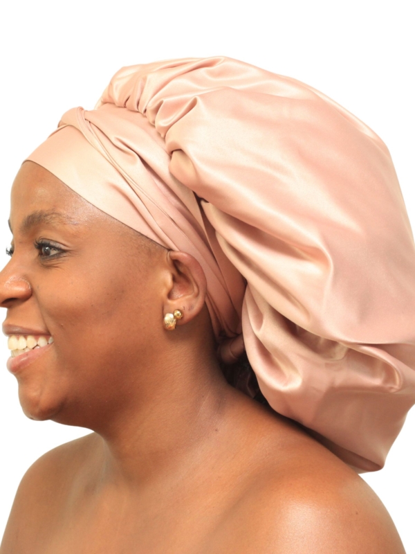 Woman wearing oversized rose gold satin bonnet designed for luxury overnight hair protection.